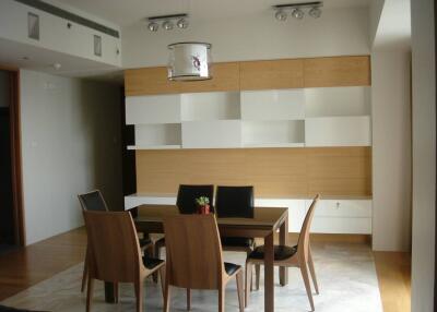 Modern dining room with wooden table and chairs, contemporary lighting and shelving units