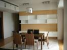 Modern dining room with wooden table and chairs, contemporary lighting and shelving units