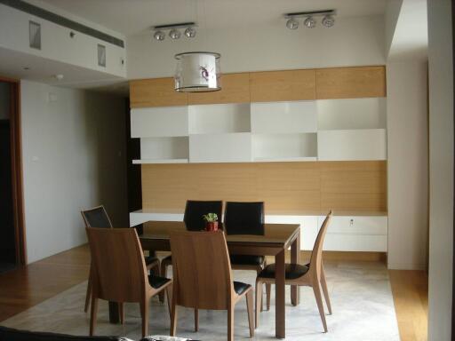 Modern dining room with wooden table and chairs, contemporary lighting and shelving units