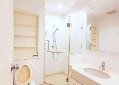 Modern bathroom with glass shower, toilet, sink, and built-in shelves