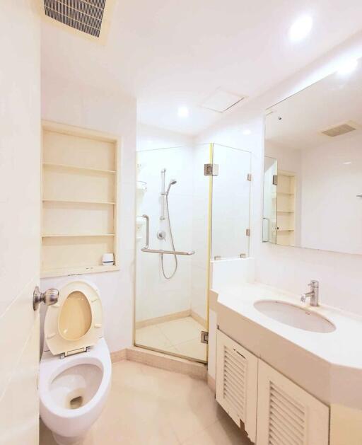 Modern bathroom with glass shower, toilet, sink, and built-in shelves