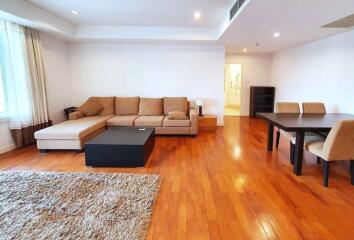 Spacious living room with hardwood floor, sofa, coffee table, dining table, and chairs