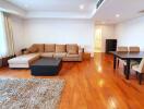 Spacious living room with hardwood floor, sofa, coffee table, dining table, and chairs