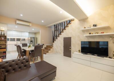 modern living room with open kitchen, dining area, and staircase