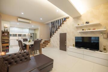 modern living room with open kitchen, dining area, and staircase