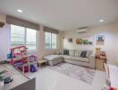 Living room with sectional sofa, children's play area, and wall-mounted decor