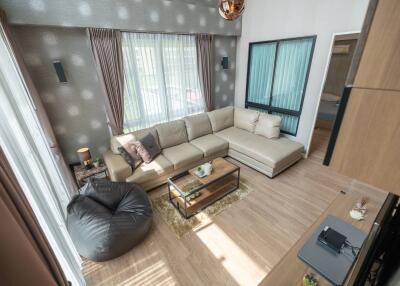 Modern living room with large windows, a sectional sofa, and a bean bag chair