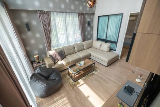 Modern living room with large windows, a sectional sofa, and a bean bag chair