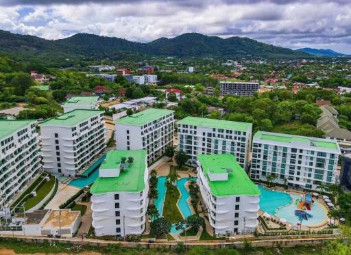 Aerial view of residential complex with green rooftops and swimming pools