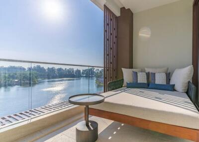 Balcony with a scenic view of water and trees, featuring a lounge bed and a small round table