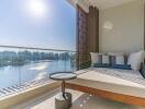 Balcony with a scenic view of water and trees, featuring a lounge bed and a small round table