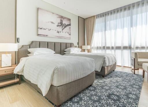 Modern bedroom with two beds, large window, and decorative carpet