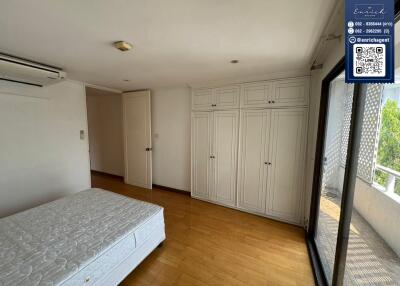 Bedroom with wooden floors, large window, and built-in wardrobes