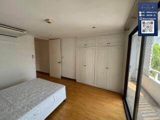 Bedroom with wooden floors, large window, and built-in wardrobes