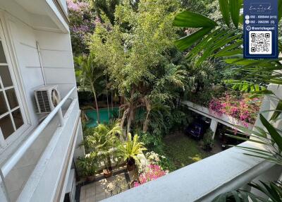 Balcony view overlooking a garden with a swimming pool and greenery