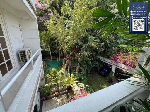 Balcony view overlooking a garden with a swimming pool and greenery