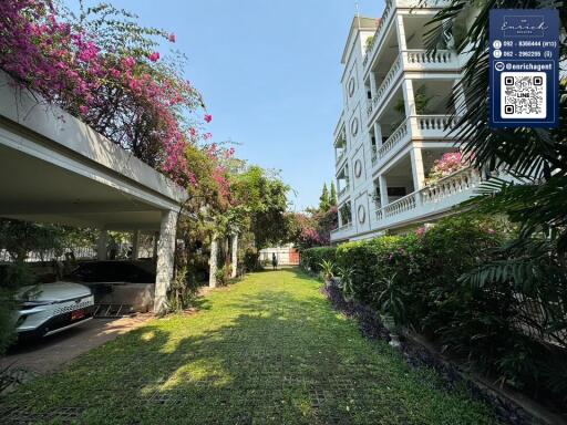 Front view of a multi-story building with garden and carport