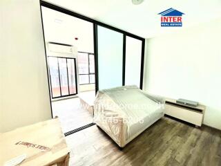 A modern bedroom with large sliding glass doors, an air conditioning unit, and wooden flooring