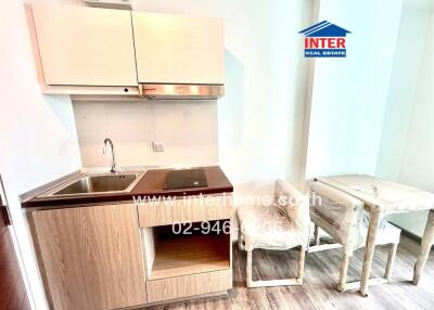 Compact kitchen with wooden cabinets, stainless steel sink, and a small dining table