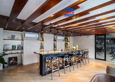 Modern kitchen area with wooden ceiling beams, air conditioners, and a large island with bar stools