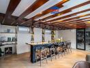 Modern kitchen area with wooden ceiling beams, air conditioners, and a large island with bar stools