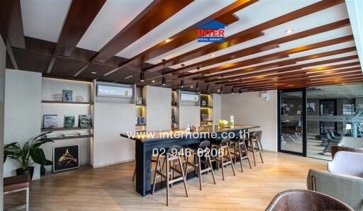 Modern kitchen area with wooden ceiling beams, air conditioners, and a large island with bar stools