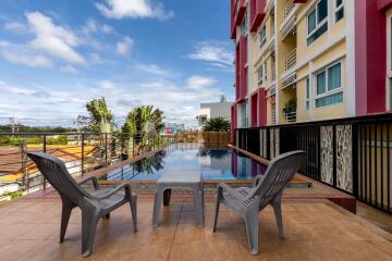 Outdoor swimming pool with chairs and building in the background