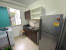 Compact kitchen with stainless steel fridge and dark cabinetry