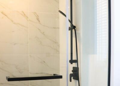 Modern bathroom with a glass-enclosed shower featuring a rainfall showerhead and marble tiles.