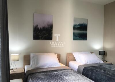 Two twin beds in a modern, well-lit bedroom with wall art