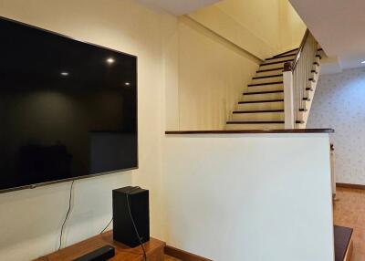 Living room with staircase and wall-mounted TV