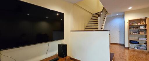 Living room with staircase and wall-mounted TV