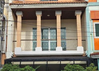 Front view of a three-story townhouse with a gated entrance and balconies.