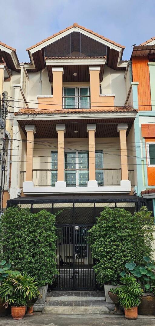 Front view of a three-story townhouse with a gated entrance and balconies.