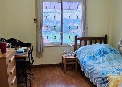 Bedroom with wooden floor, single bed, desk, and window with curtains.