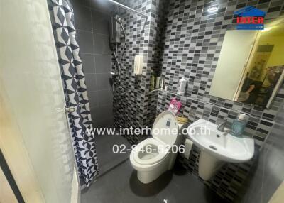 Modern bathroom with grey tiles, white fixtures, and a shower area surrounded by patterned curtains