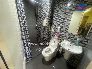 Modern bathroom with grey tiles, white fixtures, and a shower area surrounded by patterned curtains