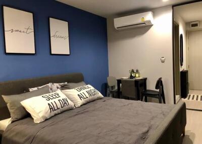 A cozy bedroom with blue accent wall, air conditioner, and workspace
