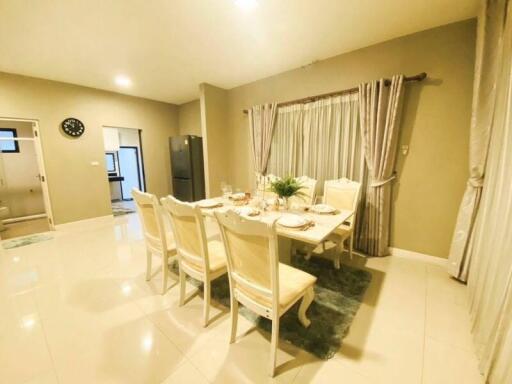 Spacious dining room with a set dining table, chairs, and elegant curtains