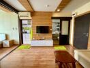 Modern living room with wooden floor, TV, and adjacent kitchen