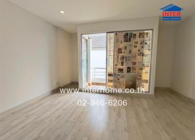 Empty bedroom with balcony access and light wood flooring