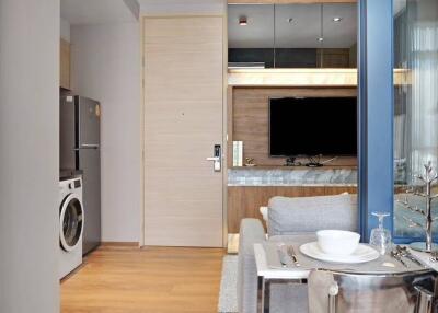 Modern living area with TV, fridge, washing machine, and dining setup