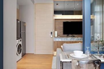 Modern living area with TV, fridge, washing machine, and dining setup