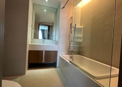 Modern bathroom with bathtub, mirrored vanity, and recessed lighting
