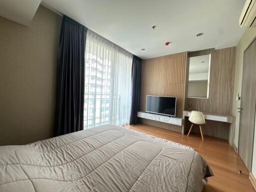 Modern bedroom with a large window, TV, and a work desk