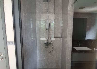 Modern bathroom shower area with grey tiles and glass partition