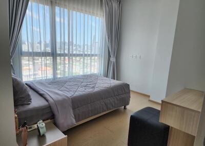 Modern bedroom with a double bed, large windows, and city view