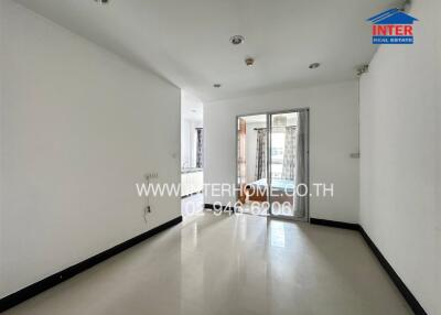 Spacious empty living room with tiled floor and sliding glass door to balcony