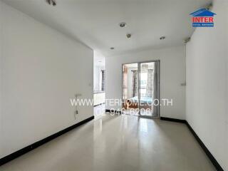 Spacious empty living room with tiled floor and sliding glass door to balcony