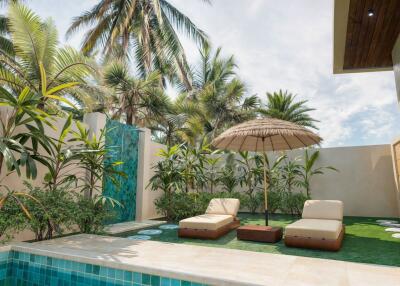 Outdoor area with pool, lounge chairs, parasol, and tropical plants